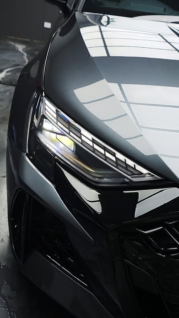 Close-up of an Audi headlight and bonnet reflecting the studio lights