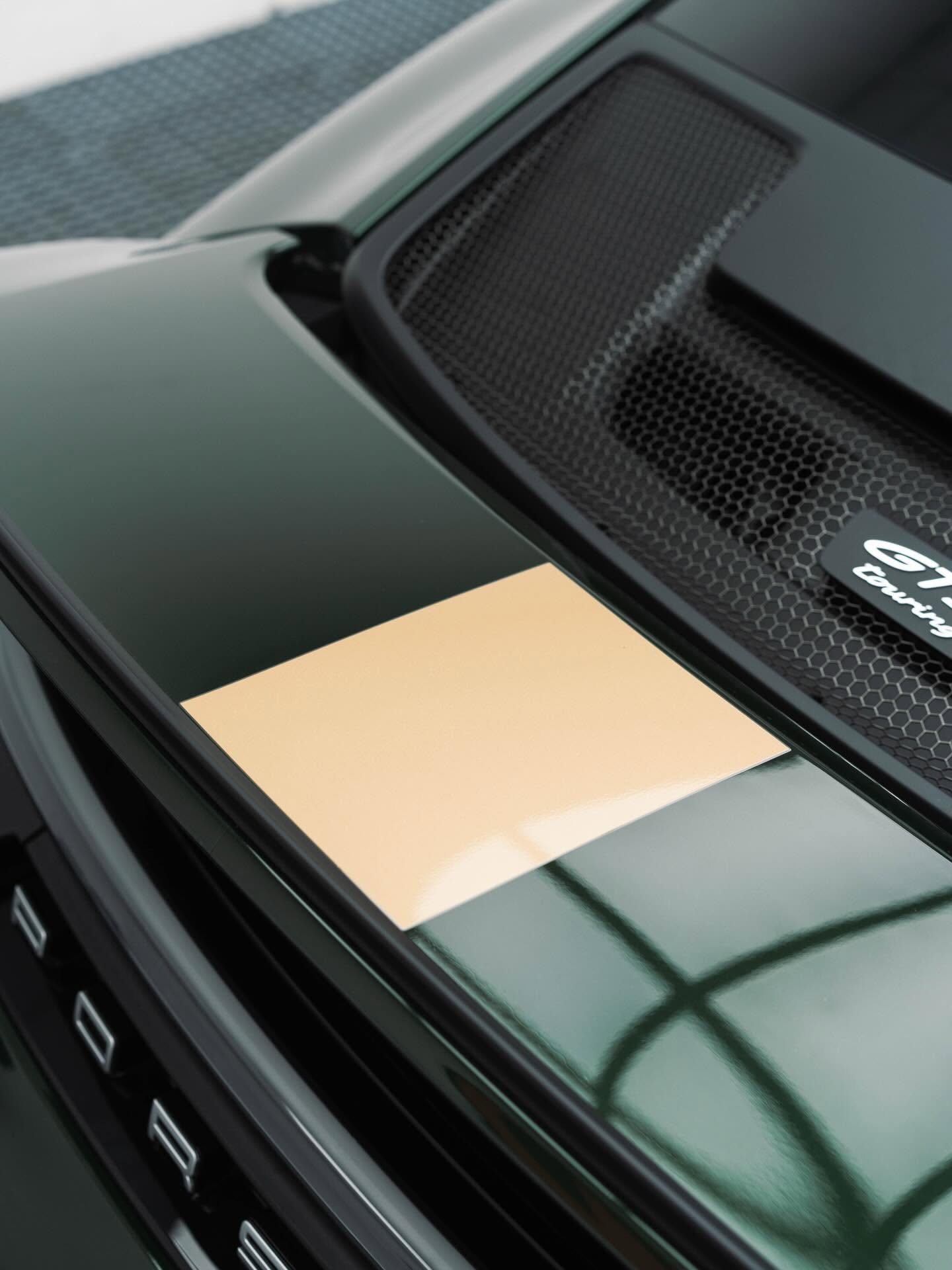 Close-up of deep green Porsche bodywork, a gold stripe and rear grille from G’ZOX Adelaide’s studio portfolio